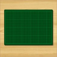 Green cutting mat isolated on wood background