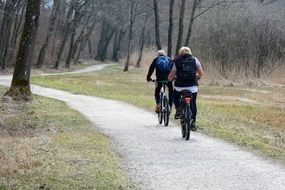 man and woman are cycling in the forest in nature