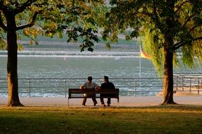 Couple is sitting together on the bench near the water