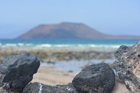 black stones in front of sea mountain