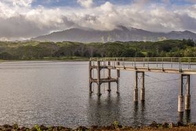 pier on lake in beautiful landscape with clouds above distant mountains