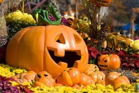 Orange plastic Halloween pumpkins among the colorful flowers