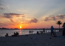 people relax on the beach during sunset