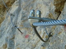 cable with metal bolts on stone wall