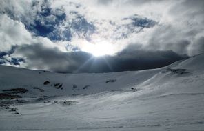 bright sun in the clouds over snow-capped mountains