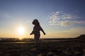 child walking on the beach at dusk
