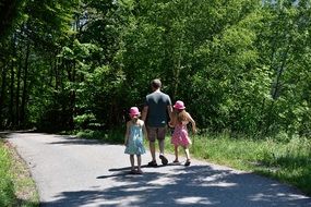 man with girls in pink hats walking