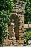 aged sculpture in stone niche in park at summer