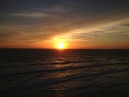 view from the beach on the ocean at sunset