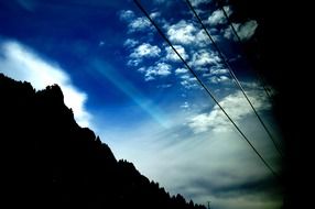 black mountain under a blue sky with clouds