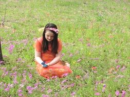 A girl sits in a clearing with wildflowers