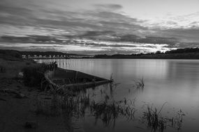 Black and white photo of a lake under white clouds