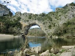 natural stone bridge with plants above the water in France