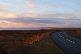 road along the ocean coast in scotland at dusk