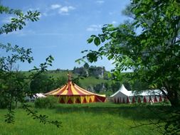 distant view of the circus tent in a green meadow