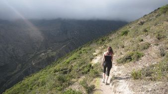 young girl walking on narrow path on mountain side