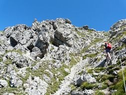 person climbing up mountain holding rope, germany, salewa klettersteig