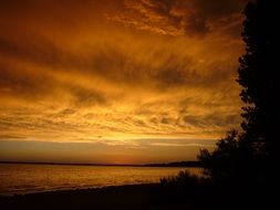 Beautiful glow of orange sunset in clouds over the lake