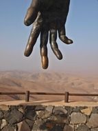 bronze hand above stone fence at mountains, spain, fuerteventura