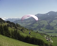 paraglider above green mountain side in scenic alpine landscape