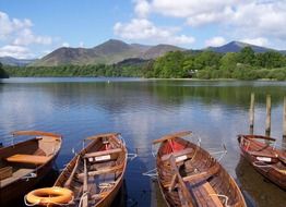 rowing boats on lake shore in view of scenic mountains