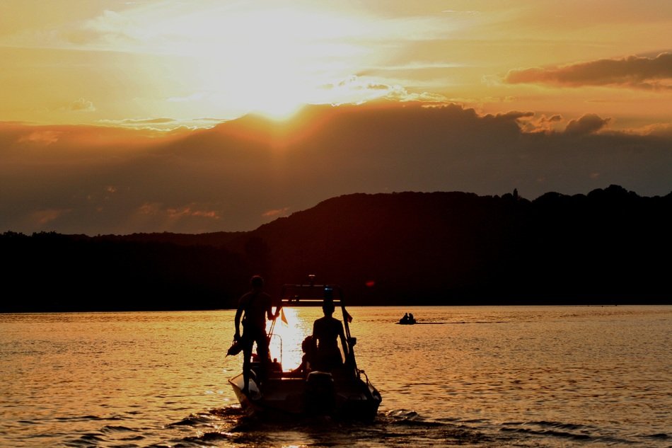 people in a boat on the background of a bright sunset
