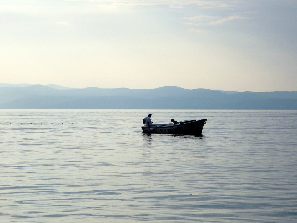people in boat on sea in view of blue coast, croatia