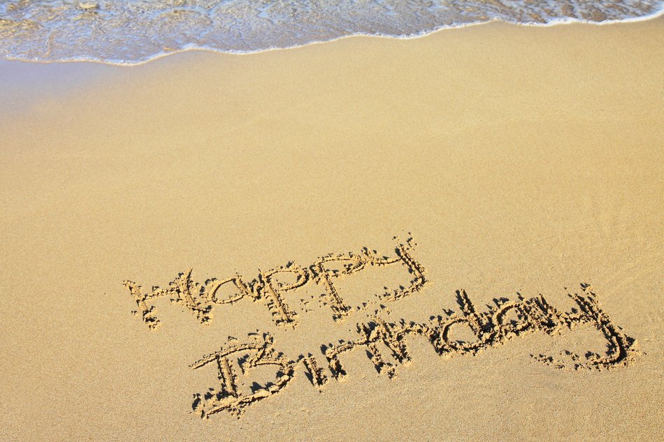 happy birthday in the sand on a sunny beach