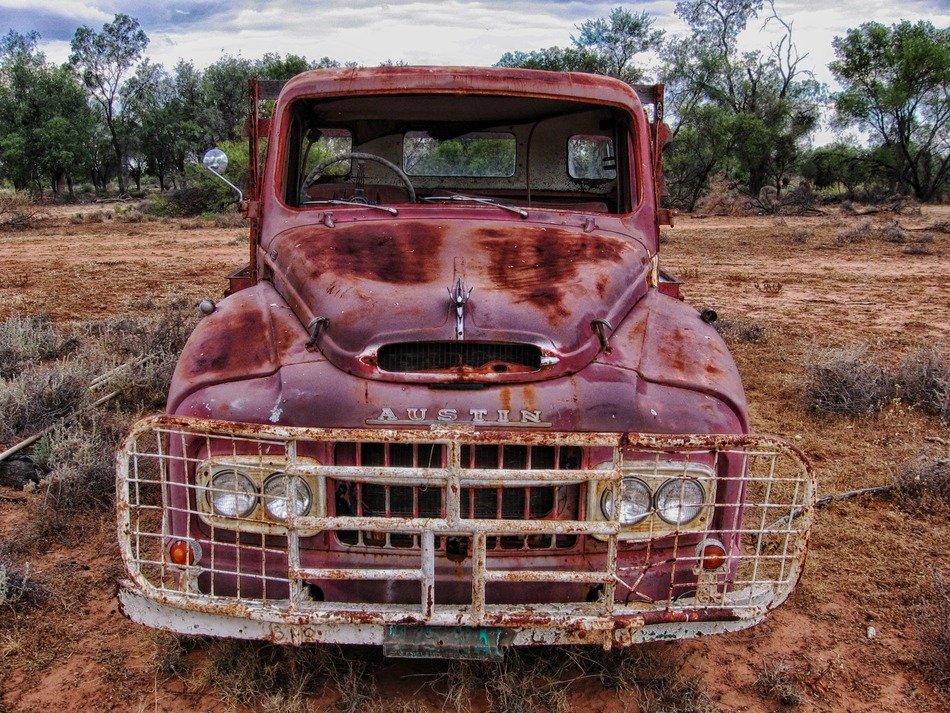 Red vintage pickup on the road among the plants in Australia