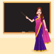Indian teacher holding a stick in front of blackboard
