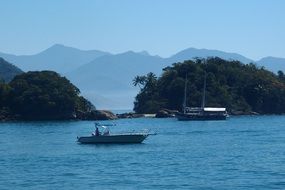 boats on blue sea in view of green islands at coast, brazil