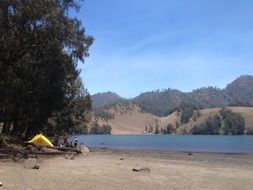 yellow tent on the shore of a mountain lake