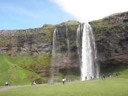 people at the foot of a waterfall in iceland