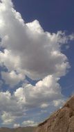 mountainside against the blue sky and white clouds