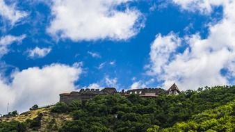 Beautiful mountain castle among the green trees near Danube at blue sky with white clouds on background in VisegrÃ¡d, Hungary