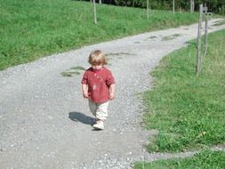 small hild walking on path at summer