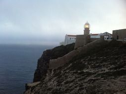 lighthouse on cliff above sea at dusk