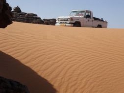 white car on sand dune at rock