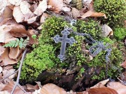 Crucifix on moss among the leaves