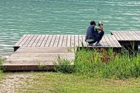 photographer on a wooden bridge near the water