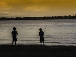 little fishermen on the river in the evening