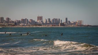 people resting in sea surf at scenic modern city, argentina, mar del plata