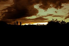 people silhouettes on the mountain at dusk
