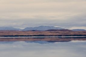 Beautiful and calm landscape with the mountains with reflections in the water under the cloudy sky