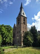 Beautiful church with a spire near the green grass and trees