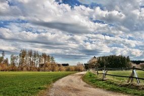 dirt road along a wooden fence and autumn forest