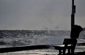 strong waves on the waterfront with a bench