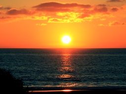 sun in the orange sky above the water during sunset