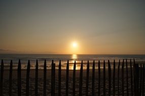 fence on the beach during sunset