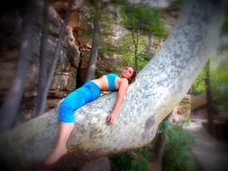 girl in blue relaxes on a tree